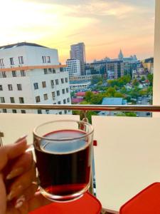 a person holding a glass of wine on a balcony at Designed like Home Apartment near Palas Mall in Iaşi