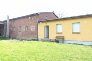 ein gelbes Gebäude mit einer Bank davor in der Unterkunft Futterhaus neben der Wasserburg Liepen in Gielow