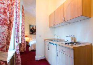 a kitchen with a sink and a room with a bed at DIRAZI Guesthouse & Apartments GmbH in Frankfurt