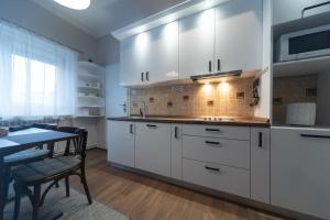 a kitchen with white cabinets and a dining table at Apartman Komfor Premium in Subotica +37 photos