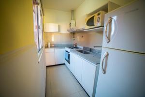 cocina pequeña con armarios blancos y nevera blanca en Complejo Los Paraísos, en Potrero de los Funes