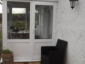 uma porta branca com uma cadeira e uma mesa em The Swallows Guest House em New Quay
