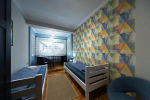 a bedroom with two beds and a colorful wall at Apartman Komfor Premium in Subotica
