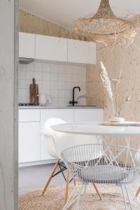 een keuken met witte kasten en een witte tafel bij NOYR. tiny house in Nunspeet