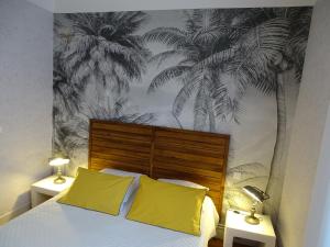 a bedroom with a bed with yellow pillows and palm trees mural at A la Vill'Adour in Dax