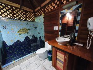 
a bathroom with a toilet, sink, and a painting on the wall at Cariblue Beach and Jungle Resort in Puerto Viejo

