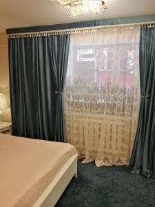 エイスクにあるдом для отпуска на Ростовскойのベッドルーム1室(グレーのカーテン、ベッド1台、シャンデリア付)