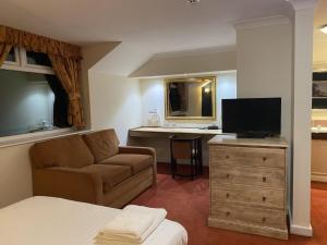 a living room with a couch and a television at The Greyhound Hotel in Leigh