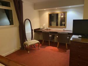 a room with a desk with chairs and a mirror at The Greyhound Hotel in Leigh