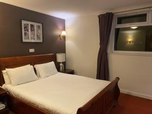 a bedroom with a large bed with a window at The Greyhound Hotel in Leigh