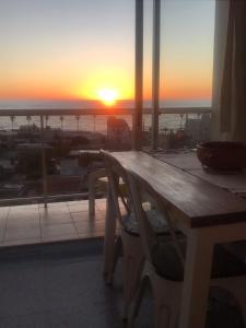- une vue sur le coucher du soleil depuis une fenêtre dotée d'un banc dans l'établissement Piriapolis apartamento, à Piriápolis