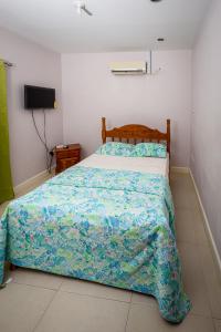 a bedroom with a bed with a blue comforter and a television at Nzingha's Villa in Buccoo