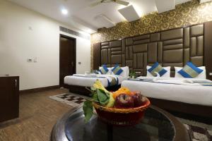 una habitación de hotel con 2 camas y un bol de fruta en una mesa en Hotel Mannat international by Mannat, en Nueva Delhi