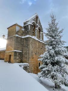 une église avec un arbre de Noël recouvert de neige devant elle dans l'établissement Hotel Rural Aguazul, à Covanera