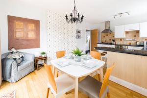 eine Küche und ein Wohnzimmer mit einem weißen Tisch und Stühlen in der Unterkunft Grundy's Lane Apartments in Malvern Wells