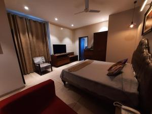a bedroom with a bed and a desk and a television at Hotel Kasauli Regency Stags Not Allowed in Kasauli