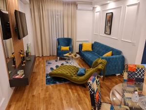 ein Wohnzimmer mit einem blauen Sofa und Stühlen in der Unterkunft Grand Lux apartman in Čačak