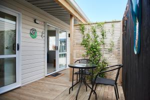 un patio con 2 sillas y una mesa en un porche en Orewa Kiwi Cabins, en Orewa