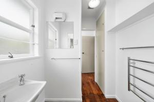 a white bathroom with a sink and a mirror at Blue Gate Cottage - Waikanae Beach Holiday Home in Waikanae +16 photos