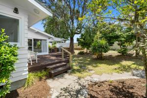 a home with a porch and stairs to a house at Blue Gate Cottage - Waikanae Beach Holiday Home in Waikanae