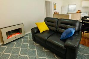 un sofá de cuero negro en una sala de estar con chimenea en Ascot Road - discover Bowral, en Bowral