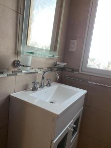 La salle de bains est pourvue d'un lavabo blanc et d'une fenêtre. dans l'établissement Las Catalpas, à Macachín