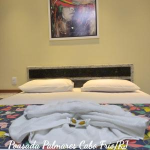 Una cama con toallas blancas encima. en Pousada Palmares, en Cabo Frío