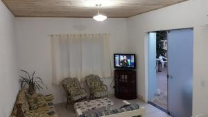 a living room with a tv and some chairs at Linda Chácara com Piscina Churrasqueira e Wi-FI in Mairinque