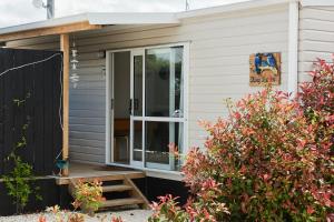 un porche cubierto en una casa con plantas en Orewa Kiwi Cabins, en Orewa