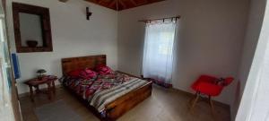 a bedroom with a bed and a red chair at Casa da Bisa - Santa Maria - Açores in Santa Bárbara