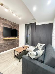 a living room with a gray couch and a table at The Works - Private one bedroom apartment in Manchester