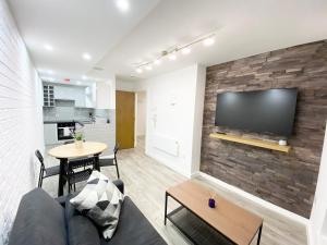 a living room with a couch and a tv on a brick wall at The Works - Private one bedroom apartment in Manchester