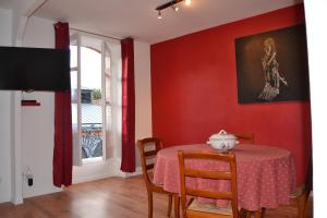 a dining room with red walls and a table and chairs at L'enfant de Bohème d'Albi, Mon-Appart Hotel-ALBI in Albi