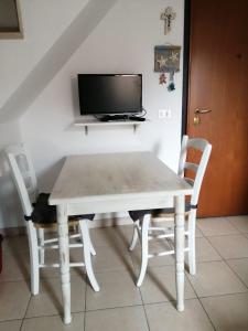 mesa blanca con 2 sillas y TV en Elisa Home Casa Vacanze, en Sottomarina