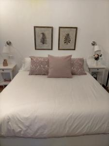 Una cama blanca con dos almohadas encima. en Casabobastro, en Ardales