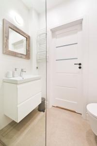 a white bathroom with a sink and a glass door at SmileApartment Świętojańska in Gdynia