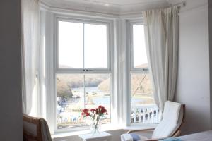 a bedroom with a large window with a view of a resort at Silver Birch in Looe