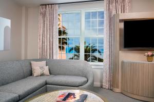 a living room with a couch and a tv and a window at The Don CeSar in St. Pete Beach