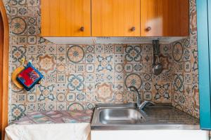una cucina con lavandino e parete piastrellata di Casa Vincenzina ad Atrani