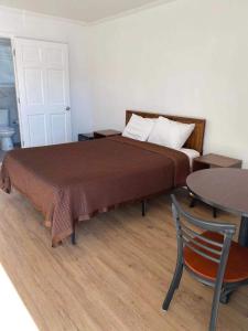 a bedroom with a bed with a table and a chair at Village Motel in Ellenville