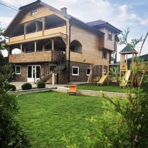 a large house with a playground in the yard at Drinska Idila apartmani in Vrhpolje
