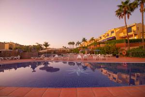una piscina en un complejo con sillas y palmeras en Sea View Meloneras Terrace Duplex +Wifi +Barbecue, en Meloneras