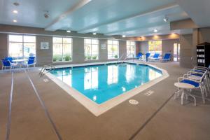 a large swimming pool in a room with chairs and tables at Holiday Inn Express & Suites - Seattle South - Tukwila by IHG in Tukwila