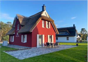 una casa rossa e bianca con tavolo e sedie di Modernes Reetdach-Ostseeferienhaus Bella Mare, Insel Usedom mit Sauna, Kamin & Sonnenterrasse a Zirchow