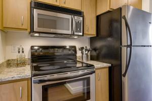 a kitchen with a stainless steel refrigerator and a microwave at Renu Suites at The Burlington Portland in Portland