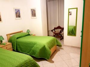 a bedroom with two beds with green sheets and a mirror at Appartamento per Turisti Mesovia in Santa Severina