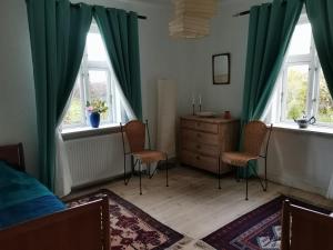 SvebølleMikrogaarden shared kitchen&bathroom的一间卧室配有两把椅子、一个梳妆台和两个窗户。