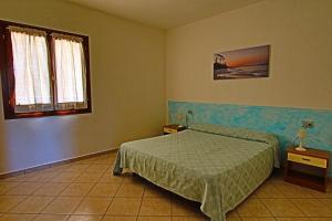 a bedroom with a bed and two tables and a window at Residence Stella Marina in San Teodoro