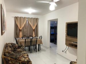 a dining room with a table and chairs and a television at Residencial Martinica I in Caraguatatuba
