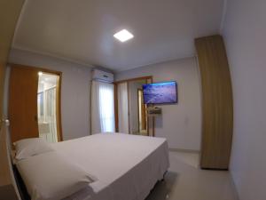 a bedroom with a bed and a tv on the wall at Flat Apart Hotel Crystal Place in Goiânia